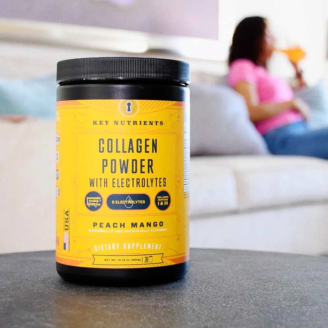 Collagen powder container on table, with a person sitting on a sofa in the background drinking.