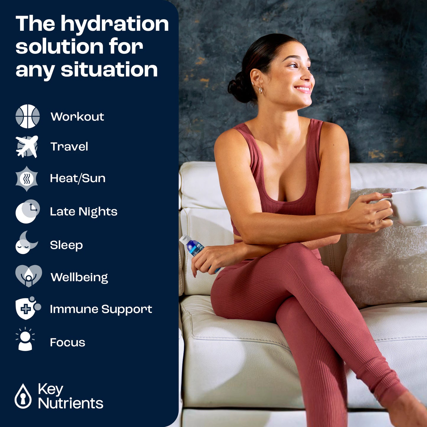 A woman in activewear holding a drink sits on a couch, showcasing the benefits of Unflavored Liquid Electrolyte Drops for hydration.