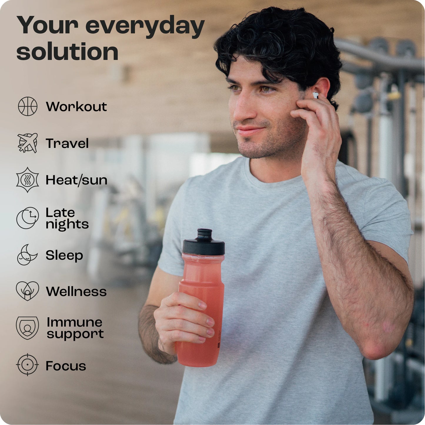 Man in gym, holding a red drink bottle with Electrolyte Recovery Plus Powder, listening to earbuds. Fitness list.