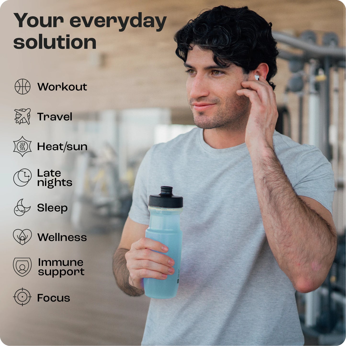 A man in the gym wears earbuds and holds a blue bottle of Electrolyte Recovery Plus Powder for wellness.