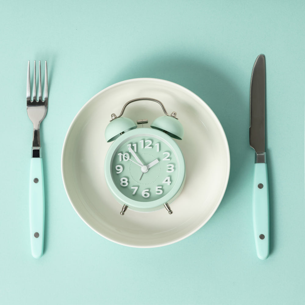 a clock on a plate next to a fork and knife