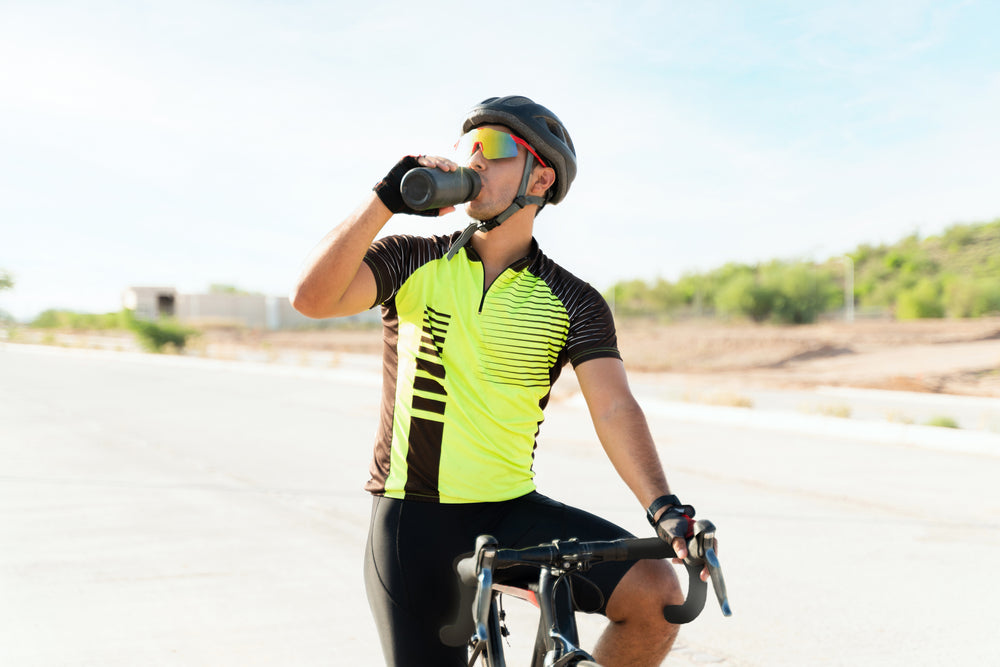 a cyclist drinking water from a reusable water bottle