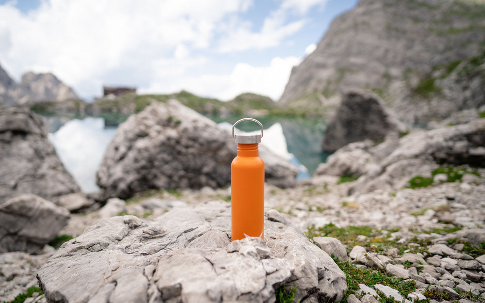 orange reusable water bottle on rock formation