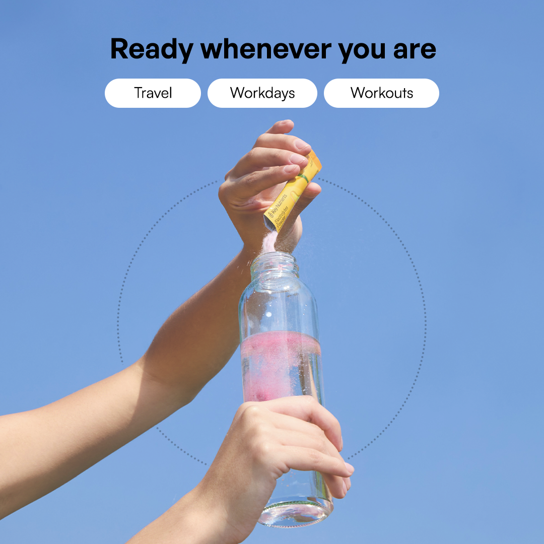 Someone adds Electrolyte Recovery Plus Powder (Sugar-Free) to a water bottle under a clear blue sky.