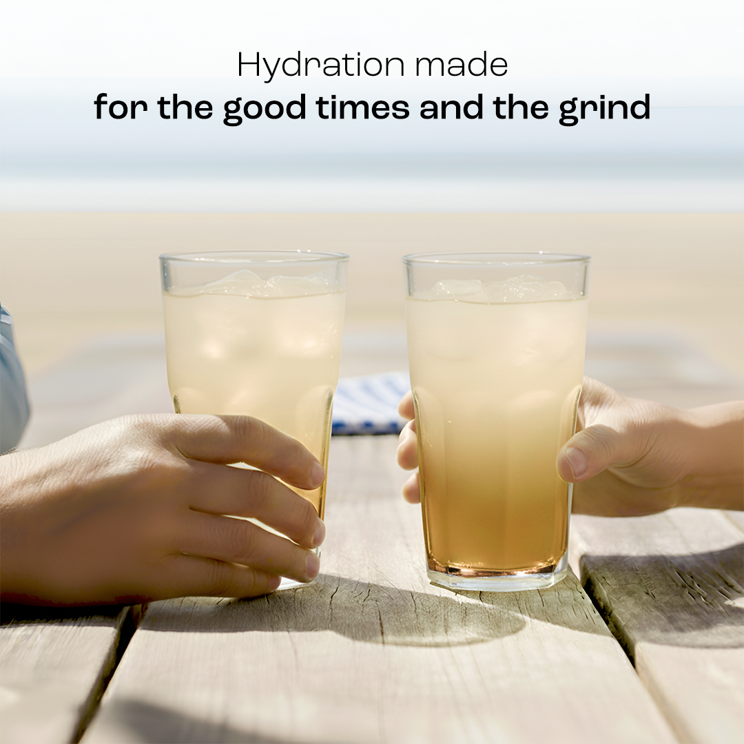 Two hands holding iced drinks by the beach: Refresh with Electrolyte Recovery Plus Powder, sugar-free.