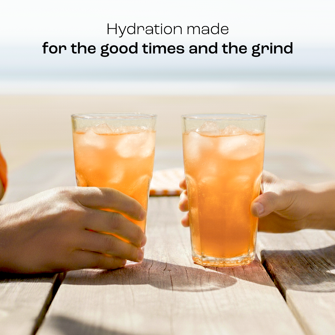 Two hands holding Electrolyte Recovery Plus Powder (Sugar-Free) on a wooden beach table, text about hydration.