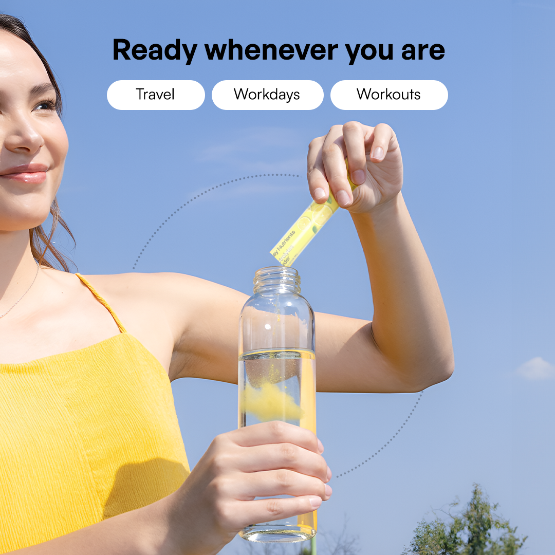 Woman in yellow dress adds Electrolytes Powder Variety Pack to water bottle outdoors for zero sugar hydration.
