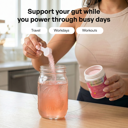 A woman pours Gut Health pink powder into a mason jar of water in a bright kitchen.